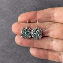 Load image into Gallery viewer, Silver earrings with blue stones held between fingers on a gray background