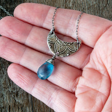 Load image into Gallery viewer, Silver crescent moon pendant with blue teardrop gemstone held in hand against a wooden background