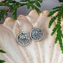 Load image into Gallery viewer, Silver earrings with intricate designs on a shell shaped dish with green leaves in the background