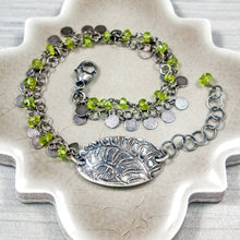 Load image into Gallery viewer, Silver bracelet with green beads and a leaf charm on a neutral surface