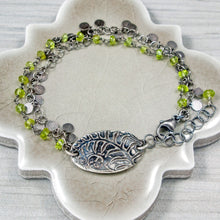 Load image into Gallery viewer, Silver bracelet with green beads and a leaf charm on a neutral surface