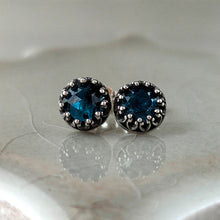 Load image into Gallery viewer, Pair of stud earrings with blue gemstones set in an intricate silver frame on a neutral beige tile.