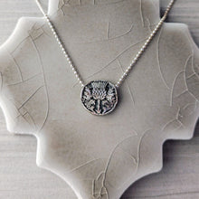 Load image into Gallery viewer, Silver necklace with a thistle pendant on a textured stone surface