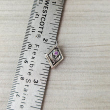 Load image into Gallery viewer, Silver pendant with a pink gemstone next to a ruler for scale