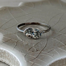 Load image into Gallery viewer, Silver ring with a detailed design on a textured ceramic surface