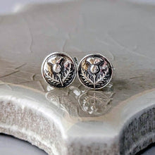 Load image into Gallery viewer, Silver floral stud earrings on a textured ceramic surface