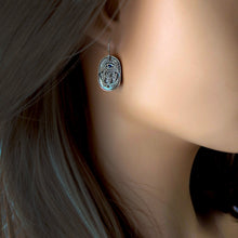 Load image into Gallery viewer, Close-up of a silver earring with a blue gemstone worn by a person.