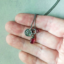 Load image into Gallery viewer, Hand holding a necklace with silver and pink gemstone charms for scale