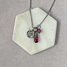 Load image into Gallery viewer, Necklace with charms on a hexagonal white stand against a gray background
