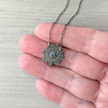 Load image into Gallery viewer, Silver mandala pendant with a blue gemstone held in a hand against a neutral background