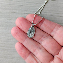 Load image into Gallery viewer, Silver pendant necklace held between fingers on a neutral background