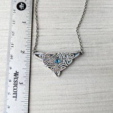 Load image into Gallery viewer, Silver necklace with intricate design and blue gemstone next to a ruler on a textured surface