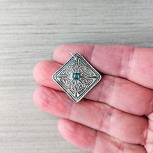 Load image into Gallery viewer, Silver pendant with a blue gemstone held between fingers on a textured gray background