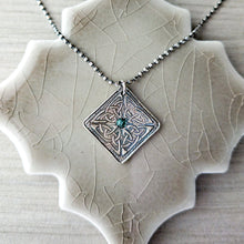 Load image into Gallery viewer, Silver geometric pendant with a green gemstone on a textured neutral surface