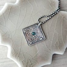 Load image into Gallery viewer, Silver pendant with intricate design and green gemstone on a textured surface