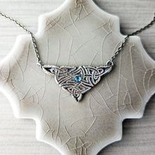 Load image into Gallery viewer, Silver necklace with a triangular pendant and blue gemstone on a textured surface