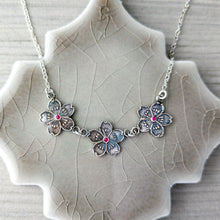 Load image into Gallery viewer, Silver floral necklace with pink rubies on a textured ceramic stand