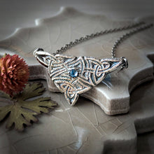 Load image into Gallery viewer, Silver geometric pendant with a blue gemstone on a textured surface with leaves and a dried flower.