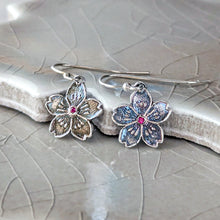 Load image into Gallery viewer, Silver flower-shaped earrings with a red gemstone on a textured surface
