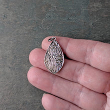 Load image into Gallery viewer, reverse side of the pendant showing a botanical textural pattern on silver