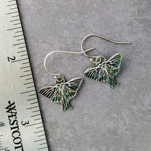 Load image into Gallery viewer, Silver Luna moth earrings on a gray surface with a ruler for scale.