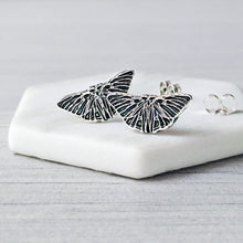 Load image into Gallery viewer, Butterfly-shaped earrings on a white stone surface with a light gray background