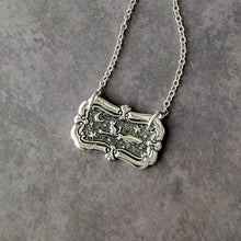 Load image into Gallery viewer, Silver necklace with an ornate pendant on a gray background