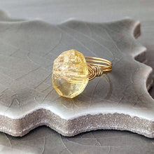 Load image into Gallery viewer, Gold ring with a large, rough-cut citrine gemstone on a textured ceramic surface