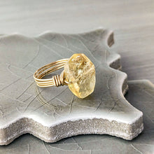 Load image into Gallery viewer, Gold ring with a large, rough-cut citrine gemstone on a textured ceramic surface