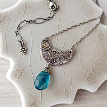 Load image into Gallery viewer, Silver crescent moon pendant with blue teardrop gemstone on a textured beige surface