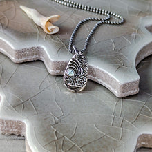 Load image into Gallery viewer, Silver pendant necklace with a blue gemstone on a textured stone surface with a tiny shell