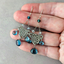 Load image into Gallery viewer, Pair of silver earrings with London blue topaz briolettes held between fingers on a neutral background