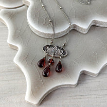 Load image into Gallery viewer, Silver necklace with red teardrop beads on a ceramic surface