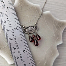 Load image into Gallery viewer, Necklace with red teardrop garnets on a textured surface next to a ruler for scale.