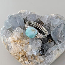 Load image into Gallery viewer, Silver wire-wrapped ring with a turquoise blue larimar stone on a crystal background
