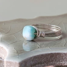 Load image into Gallery viewer, Silver ring with a turquoise blue larimar bead on a textured surface
