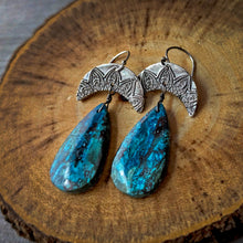 Load image into Gallery viewer, Pair of earrings with blue teardrop stones and silver crescent moon designs on a wooden surface.
