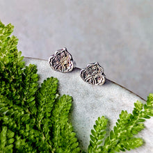 Load image into Gallery viewer, Silver floral earrings on a stone surface with green foliage
