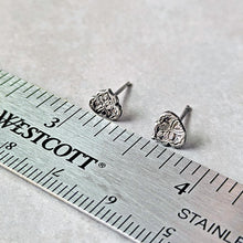 Load image into Gallery viewer, Silver floral stud earrings on a ruler for scale.