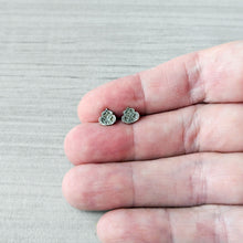 Load image into Gallery viewer, Small silver earrings held between fingers on a light gray background