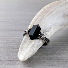 Load image into Gallery viewer, A silver and onyx ring sits on a white shell fragment