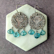 Load image into Gallery viewer, Pair of silver earrings with an embossed owl design and blue gemstones on a hexagonal stone surface.