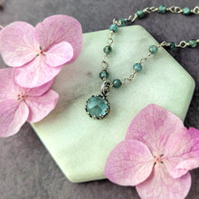 Load image into Gallery viewer, Necklace with a blue pendant on a white stone surrounded by pink flowers