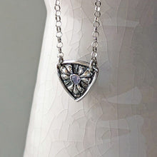 Load image into Gallery viewer, Silver necklace with a shield-shaped pendant on a ceramic prop
