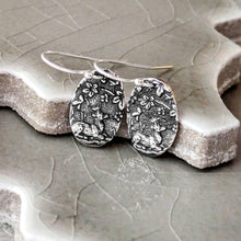 Load image into Gallery viewer, Silver floral earrings on a textured ceramic surface