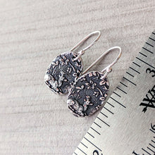 Load image into Gallery viewer, Silver textured earrings on a gray surface with a ruler for scale.