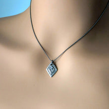 Load image into Gallery viewer, A fine silver thistle pendant with a blue tanzanite centerpiece, attached to a silver chain, displayed on a mannequin neck
