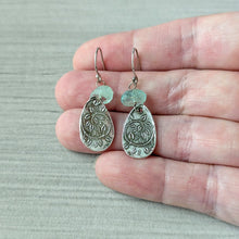 Load image into Gallery viewer, Silver teardrop earrings with green beads held between fingers on a light gray background