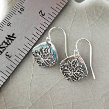 Load image into Gallery viewer, Silver floral earrings on a textured surface with a ruler for scale.