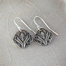 Load image into Gallery viewer, Silver patterned earrings on a textured stone surface